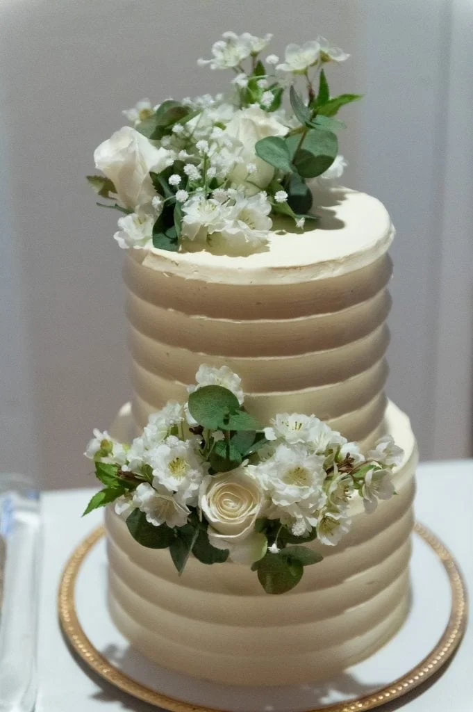 Bryllupskake med hvite blomster og grønne blader, dekorert for en spesiell anledning.