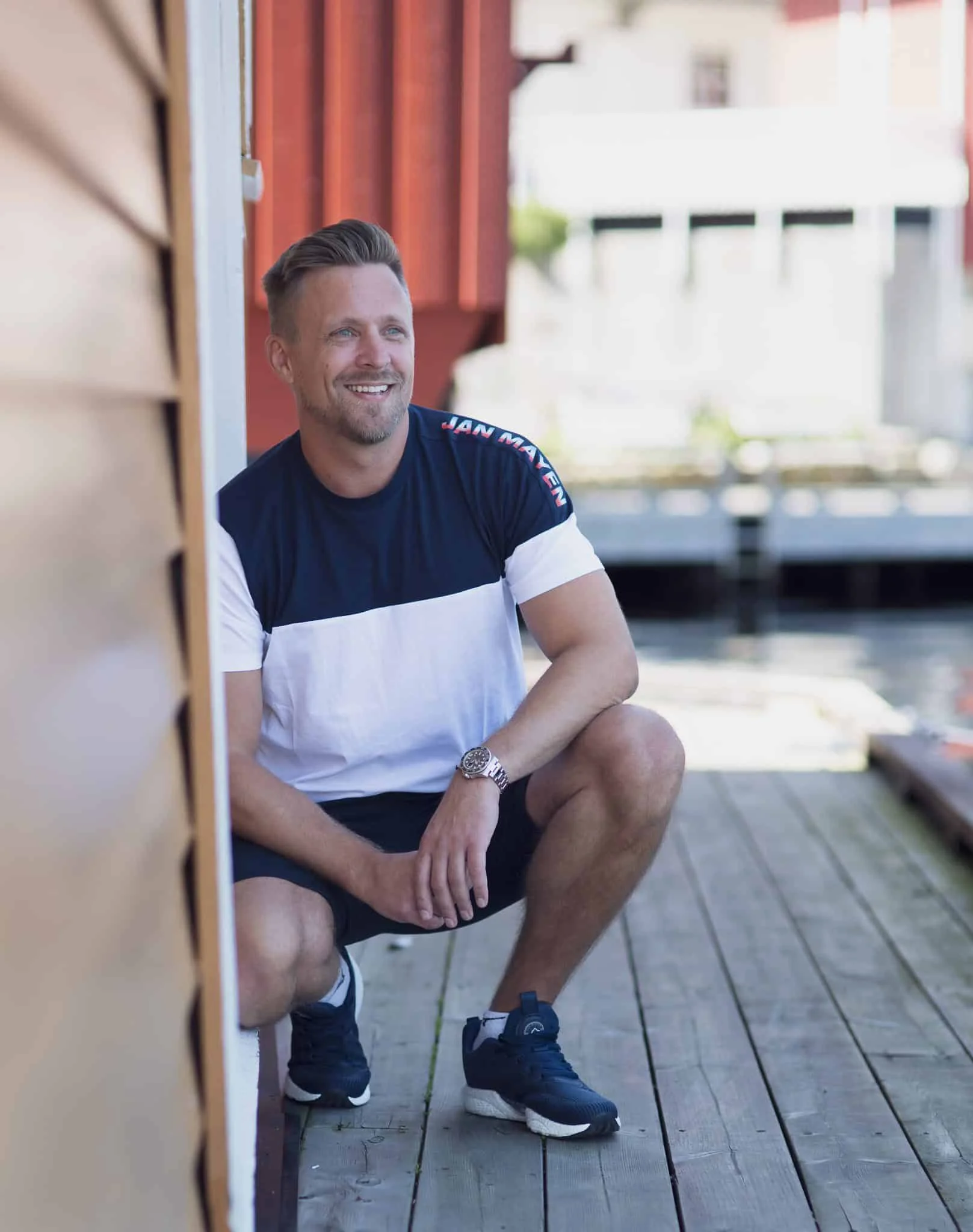 Energisk mann smiler mens han nyter en dag ved vannet, omgitt av fargerike bygninger og en rolig atm.