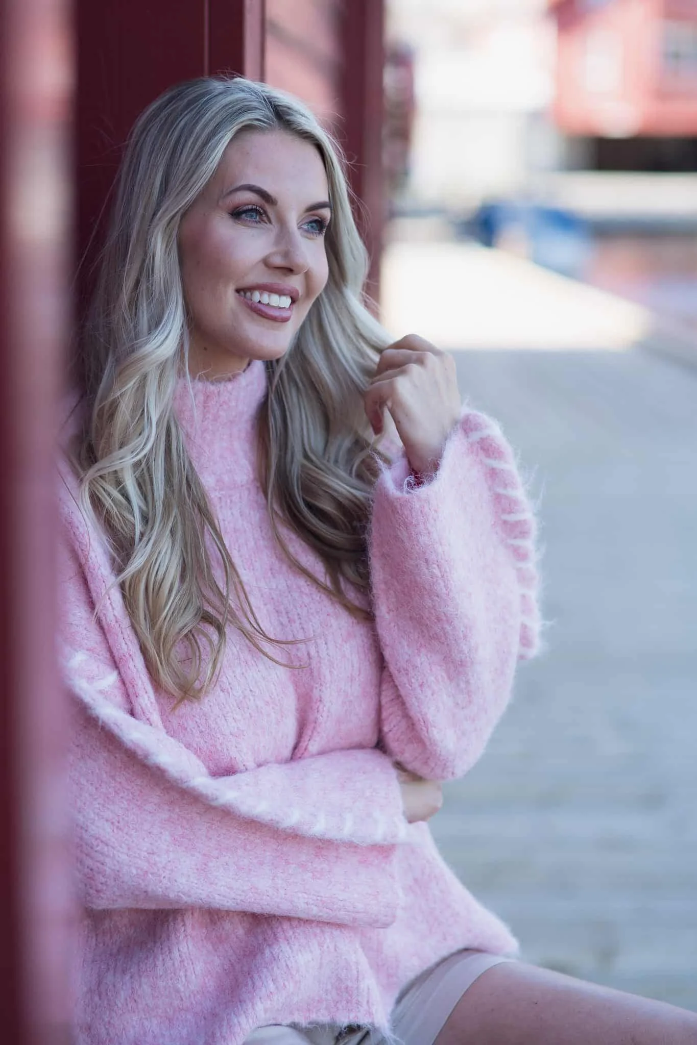 Smilende kvinne i rosa genser som ser ut mot horisonten, symbol på evig minne og kjærlighet.