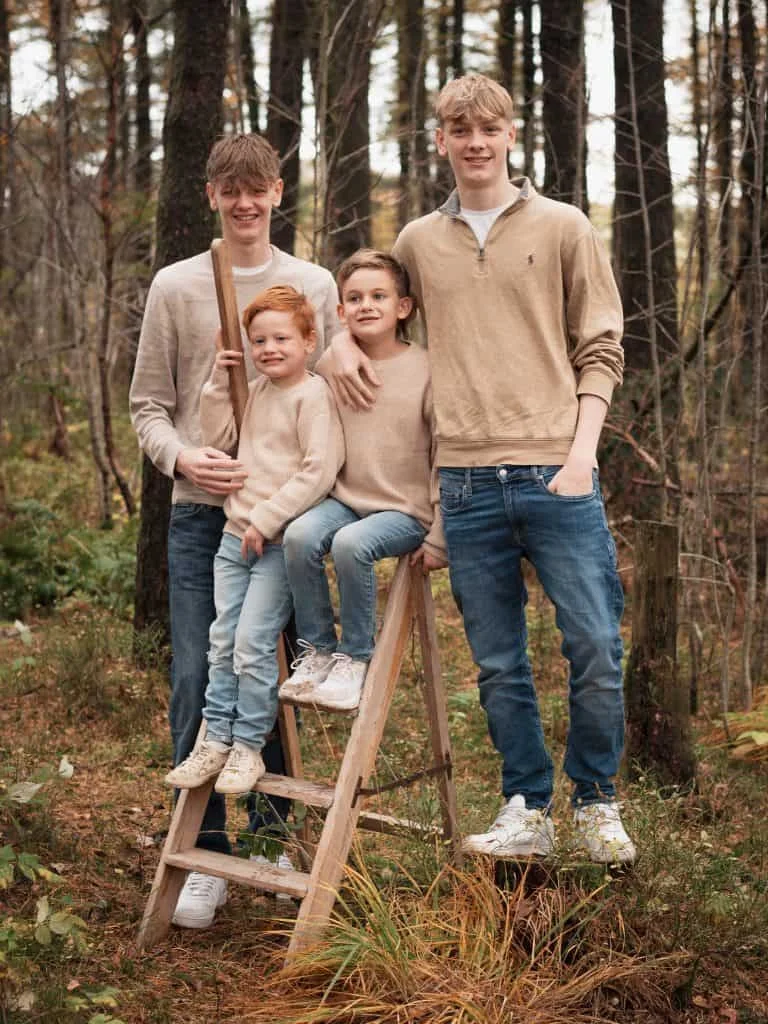 Fire brødre i ulike aldre poserer sammen i en skog under en utendørs familie- og barnefotografering hos en profesjonell fotograf.
