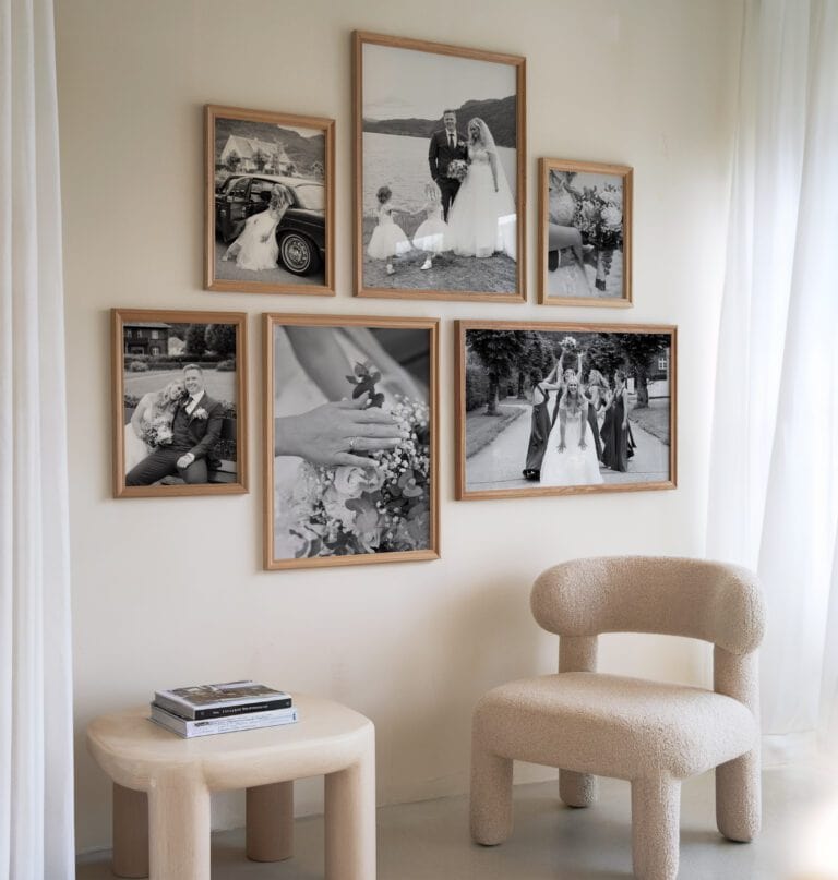 Vegg med seks innrammede svart-hvitt bryllupsbilder i treverk over en moderne stol, perfekt for inspirasjon til nyfødtfotografering i studio.