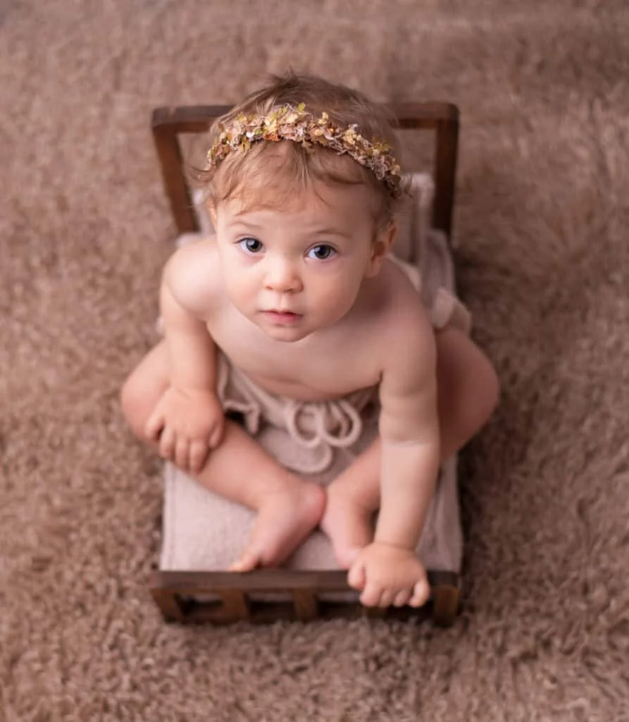 1 års foto av baby på brunt teppe